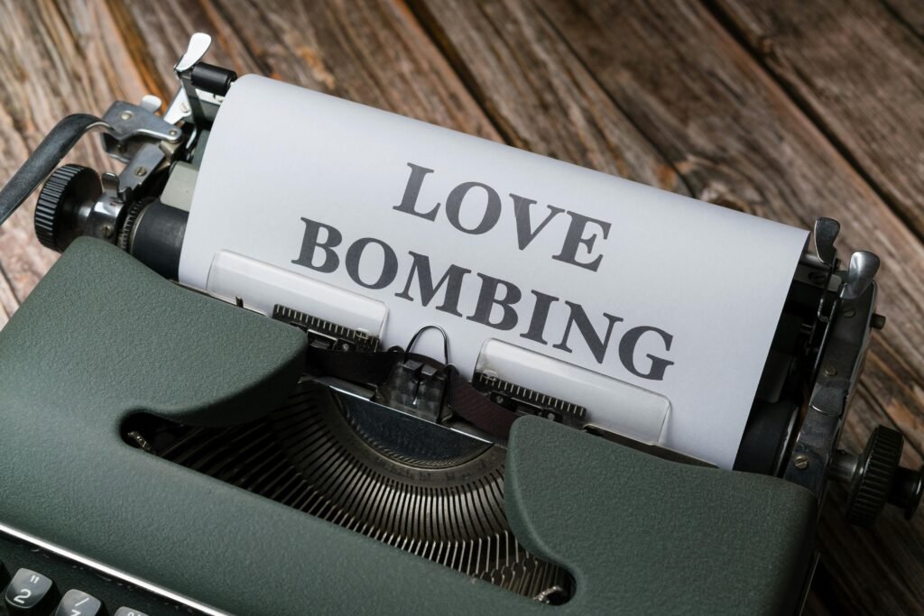 Close-up of a vintage typewriter printing 'Love Bombing' on paper, placed on a wooden desk.