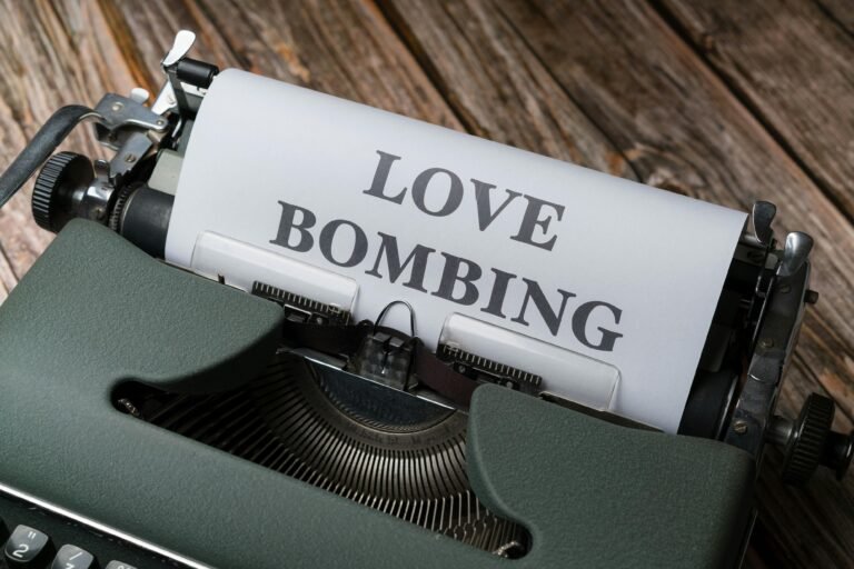 Close-up of a vintage typewriter printing 'Love Bombing' on paper, placed on a wooden desk.
